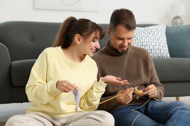 Photo of Woman teaching her boyfriend how to knit on floor at home