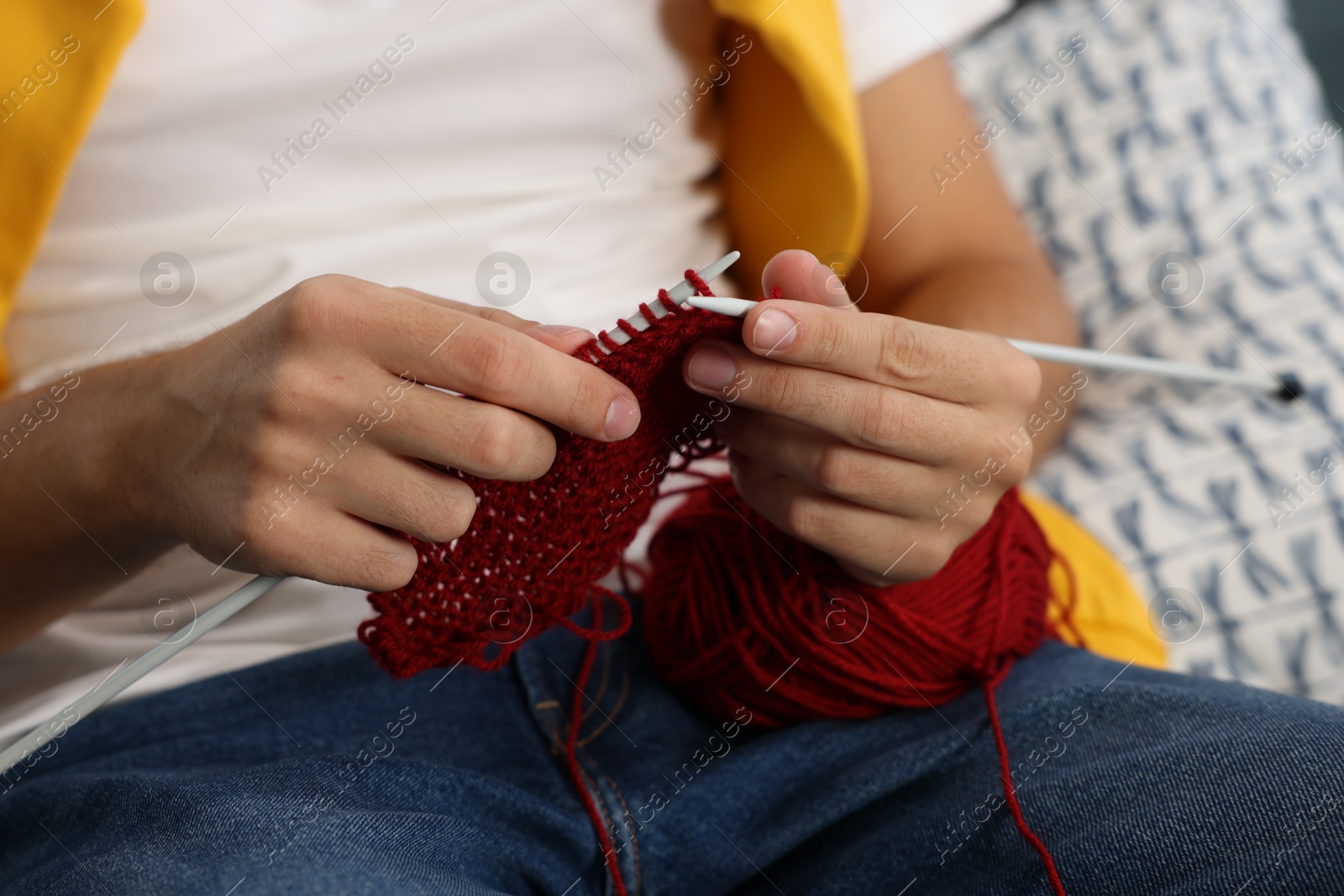 Photo of Man knitting with needles at home, closeup