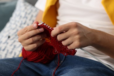 Photo of Man knitting with needles at home, closeup