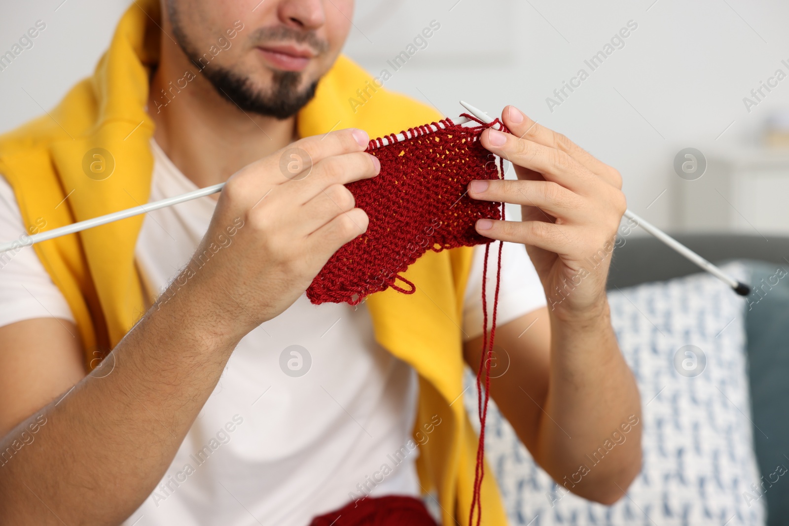 Photo of Man knitting with needles at home, closeup