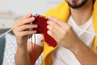 Man knitting with needles at home, closeup