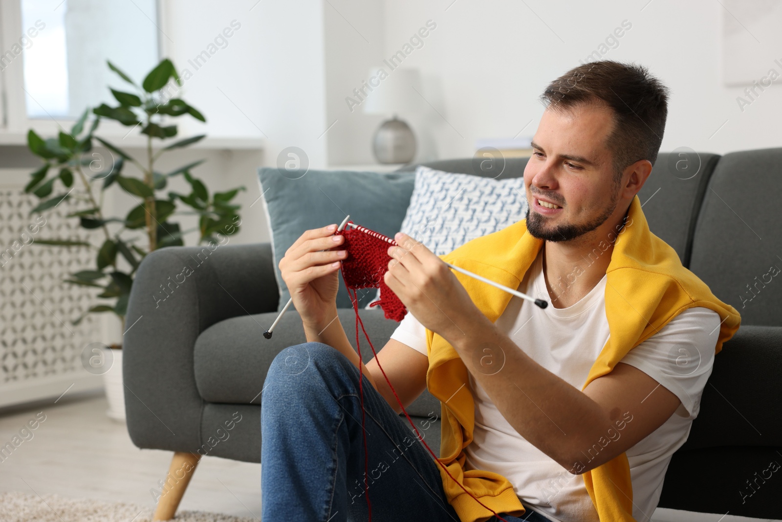 Photo of Man knitting with needles on floor at home