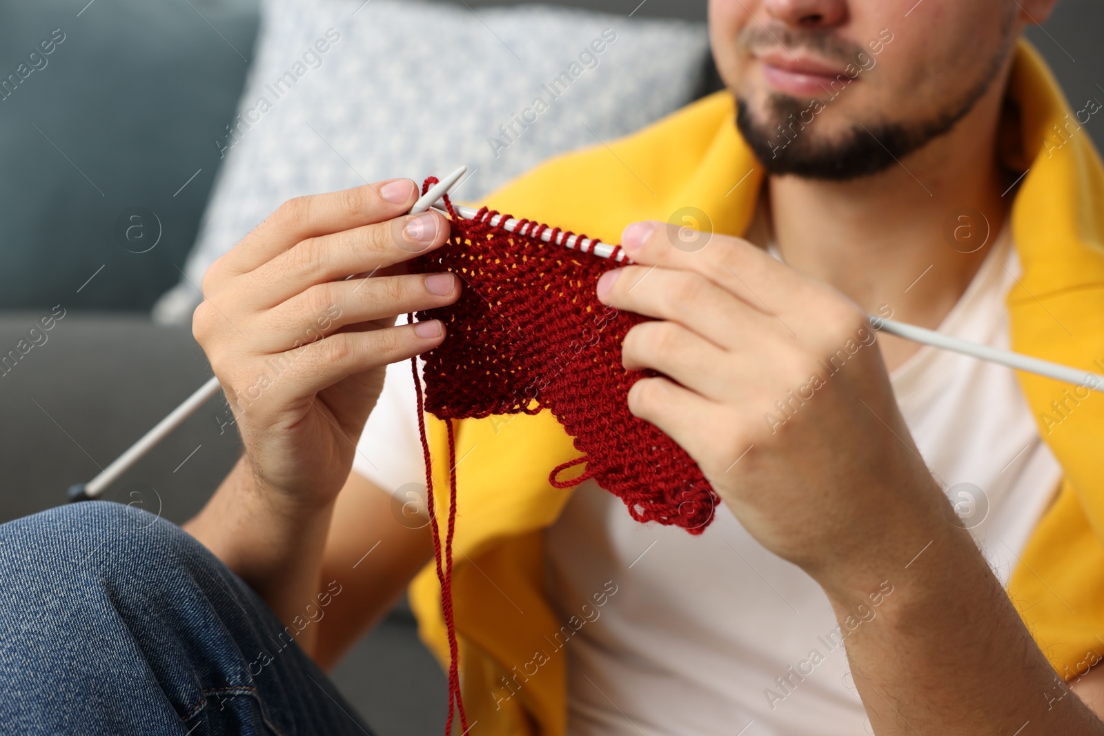 Photo of Man knitting with needles at home, closeup