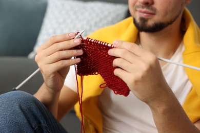 Man knitting with needles at home, closeup