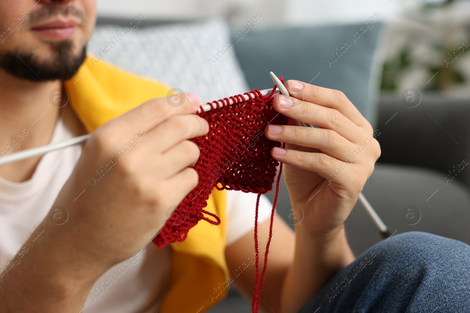 Photo of Man knitting with needles at home, closeup