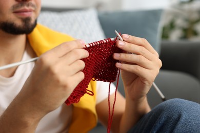 Man knitting with needles at home, closeup