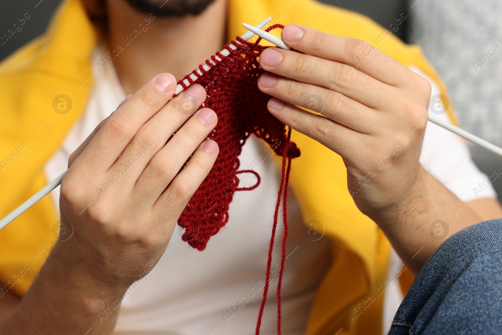 Photo of Man knitting with needles at home, closeup