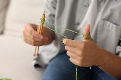 Photo of Man knitting with needles at home, closeup