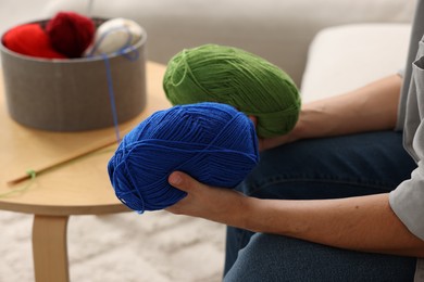 Man with colorful yarns at home, closeup. Knitting material