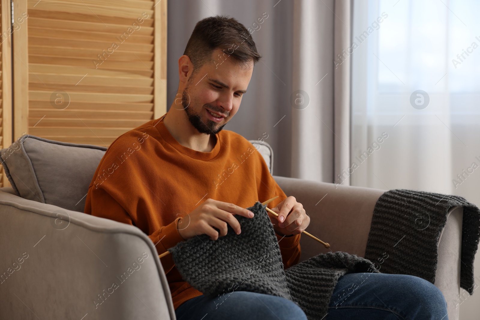 Photo of Man knitting with needles in armchair at home