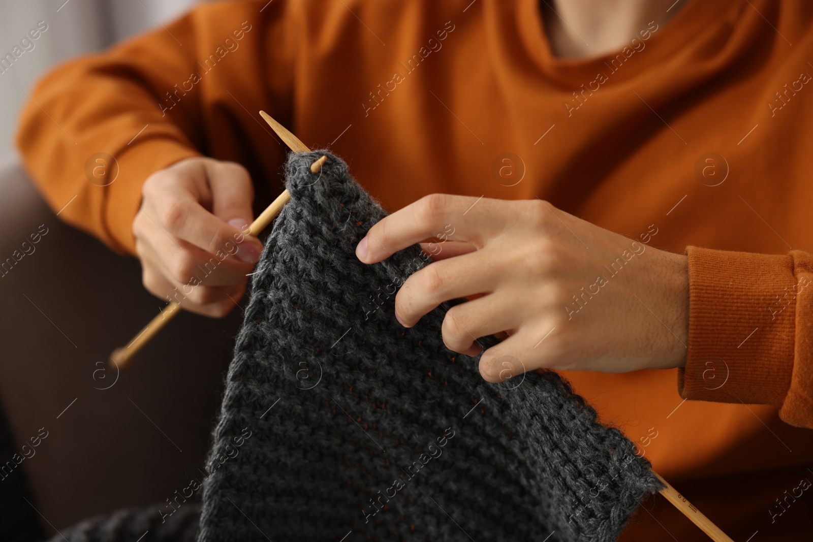 Photo of Man knitting with needles at home, closeup