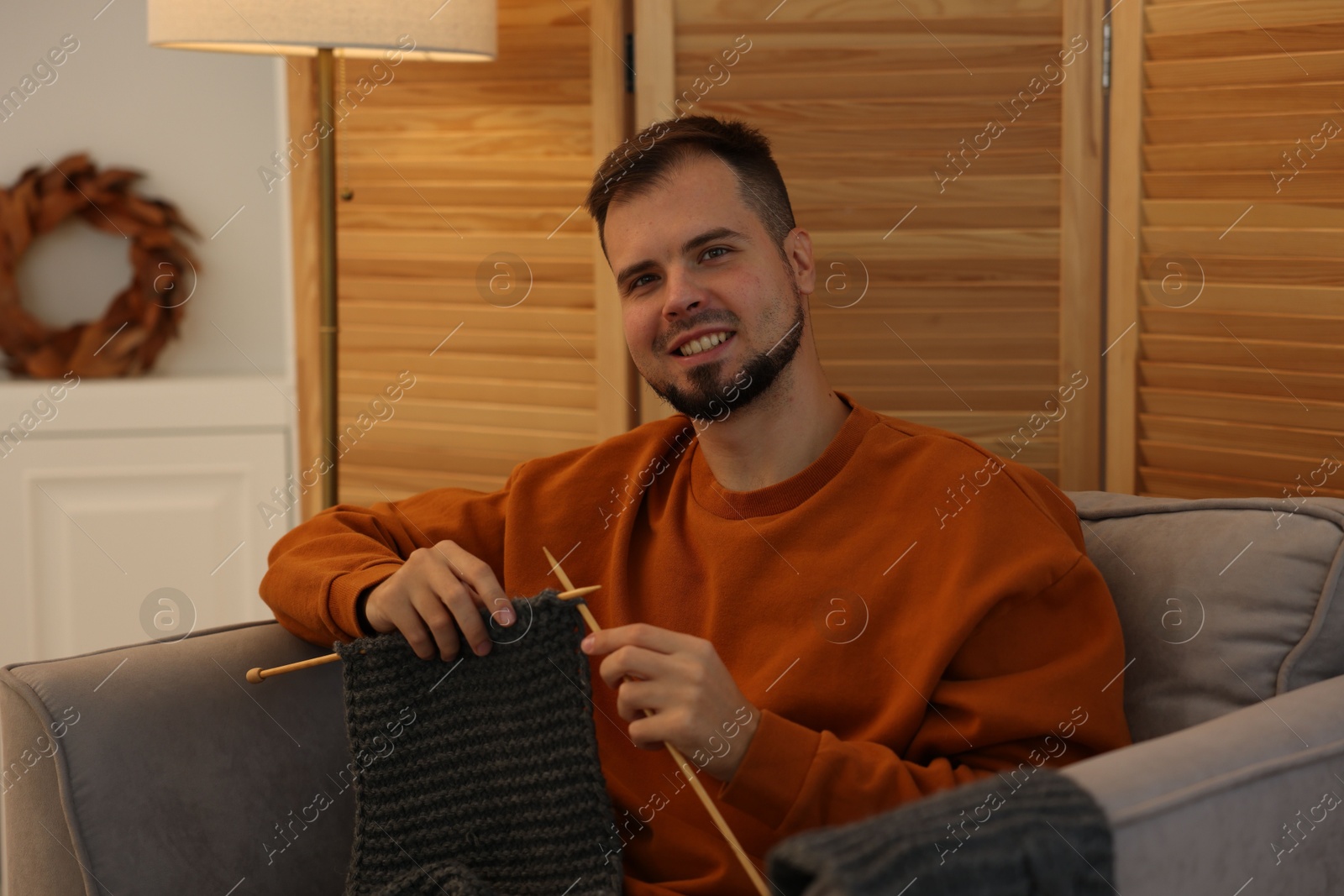 Photo of Man knitting with needles in armchair at home