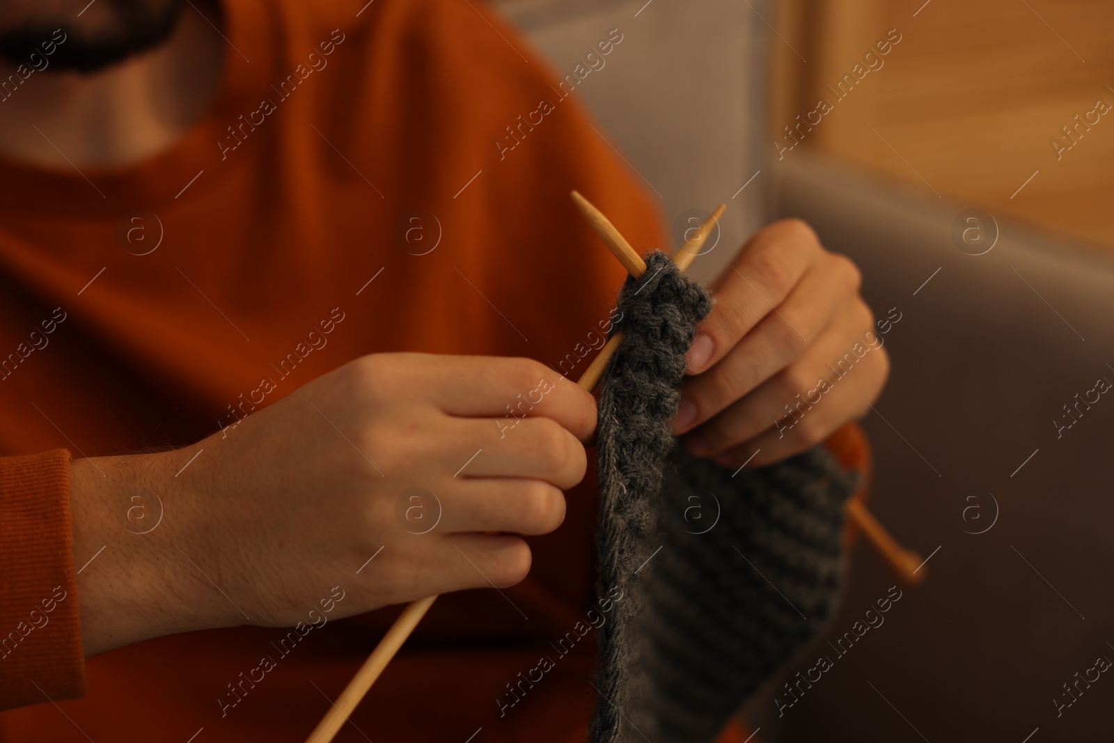 Photo of Man knitting with needles at home, closeup