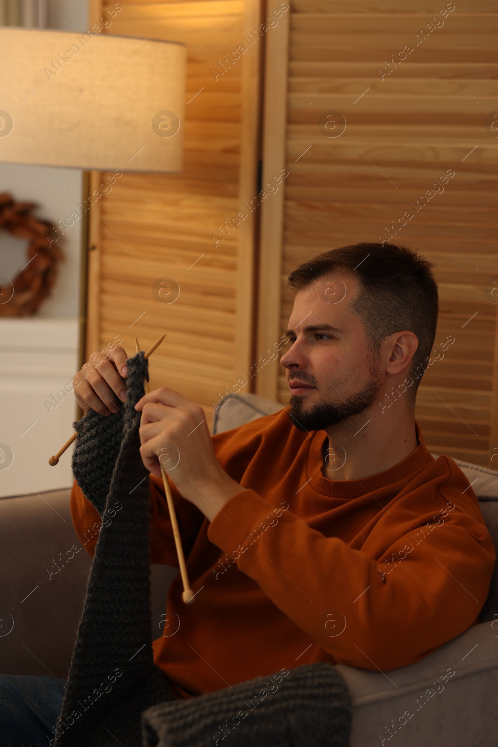 Photo of Man knitting with needles in armchair at home