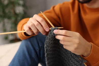 Man knitting with needles at home, closeup