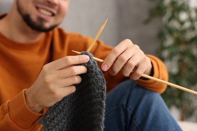 Man knitting with needles at home, closeup