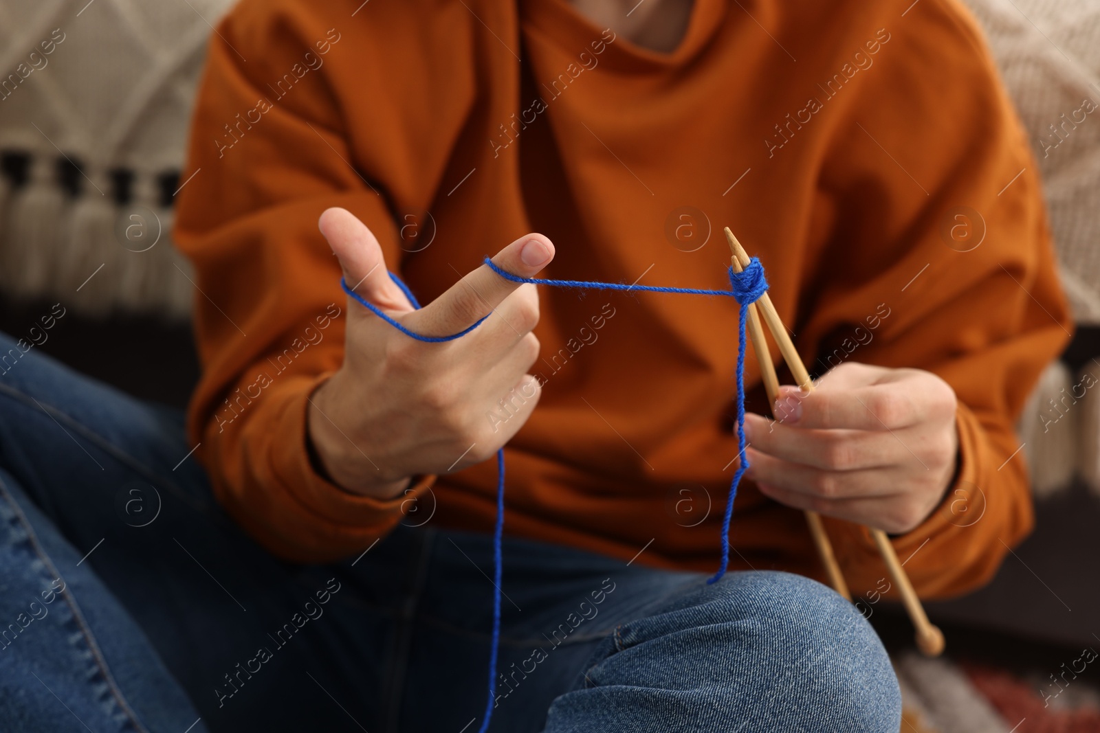 Photo of Man knitting with needles at home, closeup