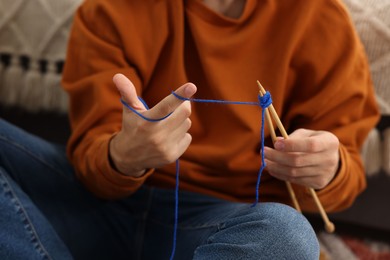 Man knitting with needles at home, closeup