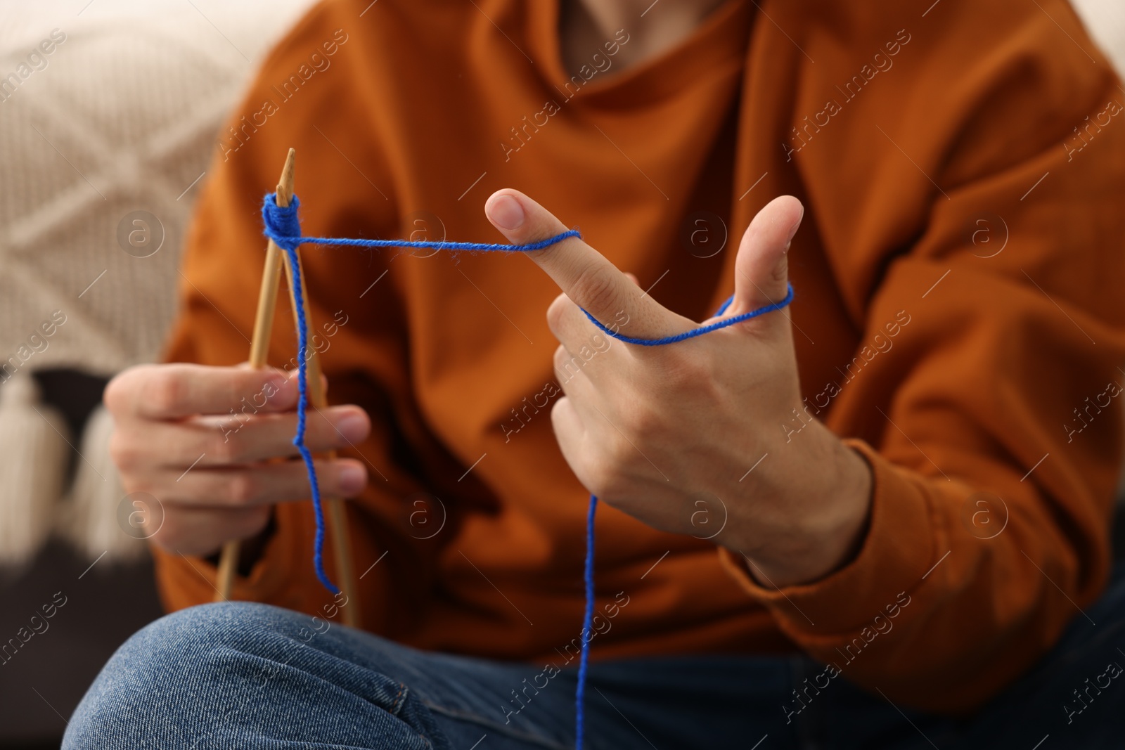 Photo of Man knitting with needles at home, closeup