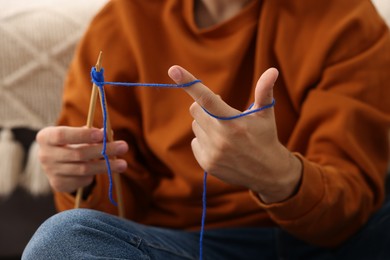 Photo of Man knitting with needles at home, closeup