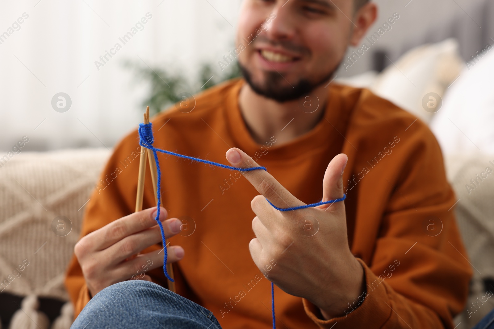 Photo of Man knitting with needles at home, closeup