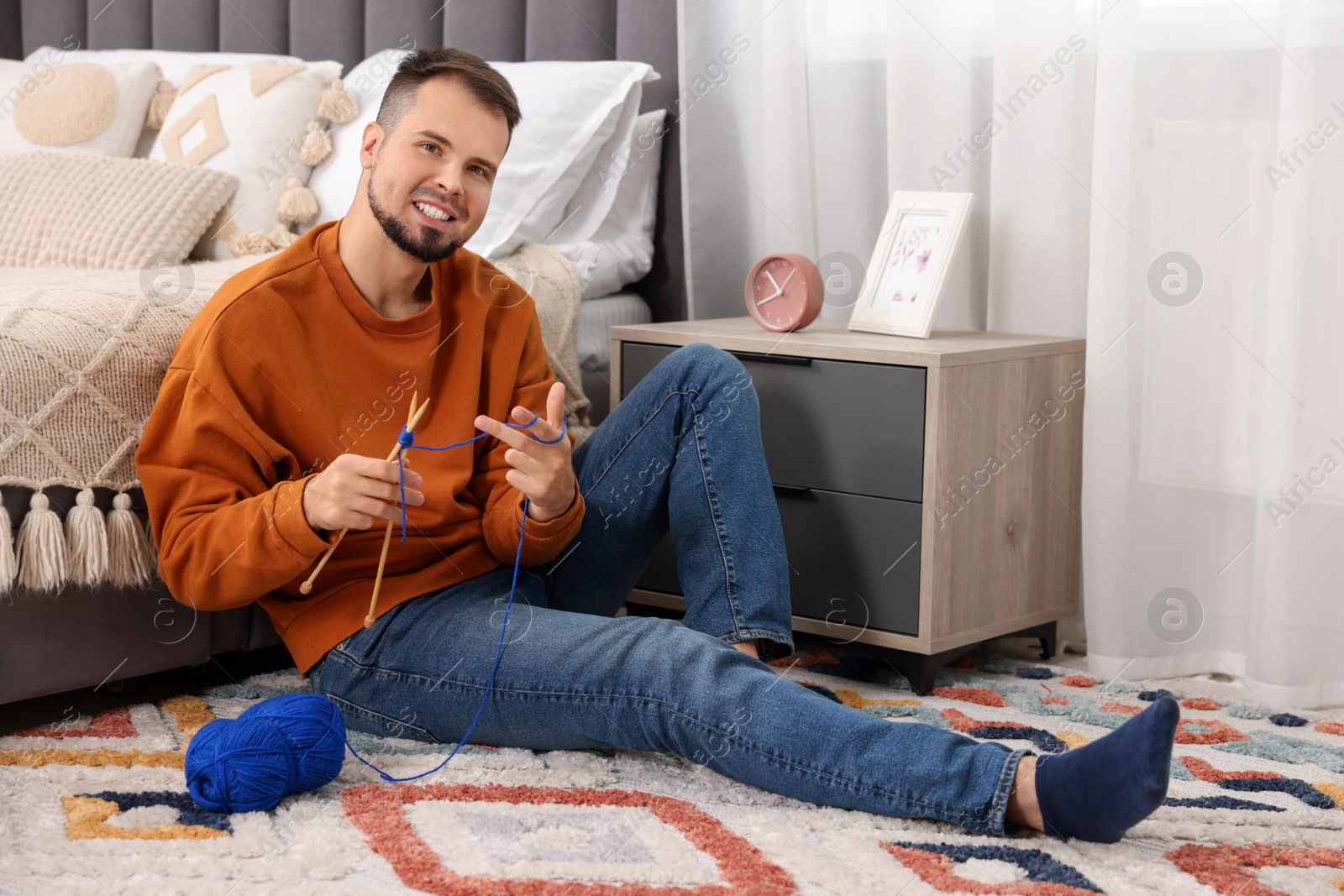 Photo of Man knitting with needles on floor at home