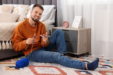 Photo of Man knitting with needles on floor at home