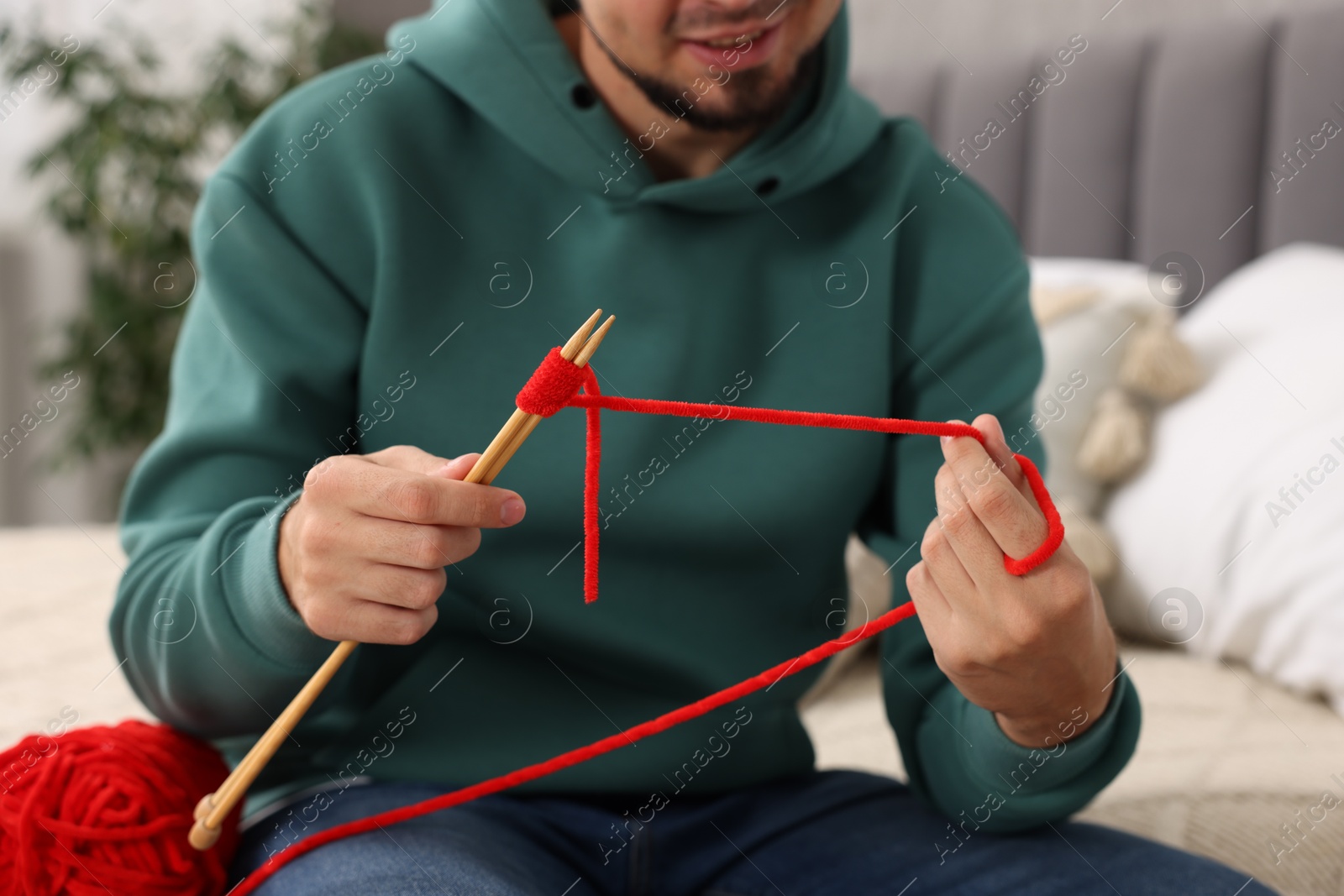 Photo of Man knitting with needles at home, closeup