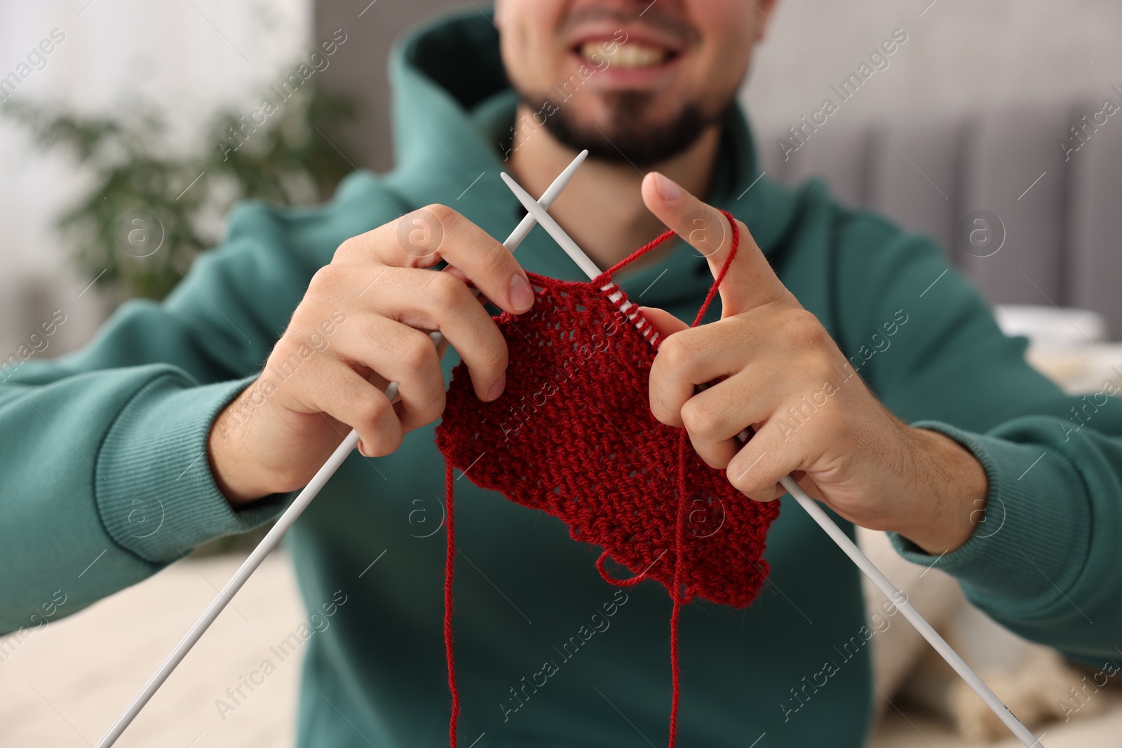 Photo of Man knitting with needles at home, closeup