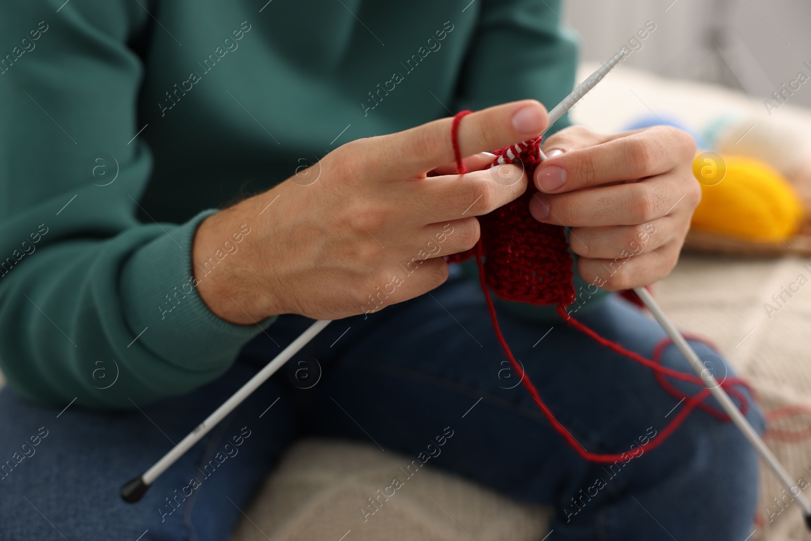 Photo of Man knitting with needles at home, closeup