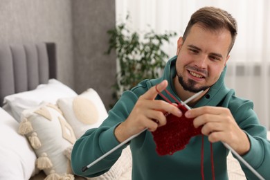 Happy man knitting with needles at home