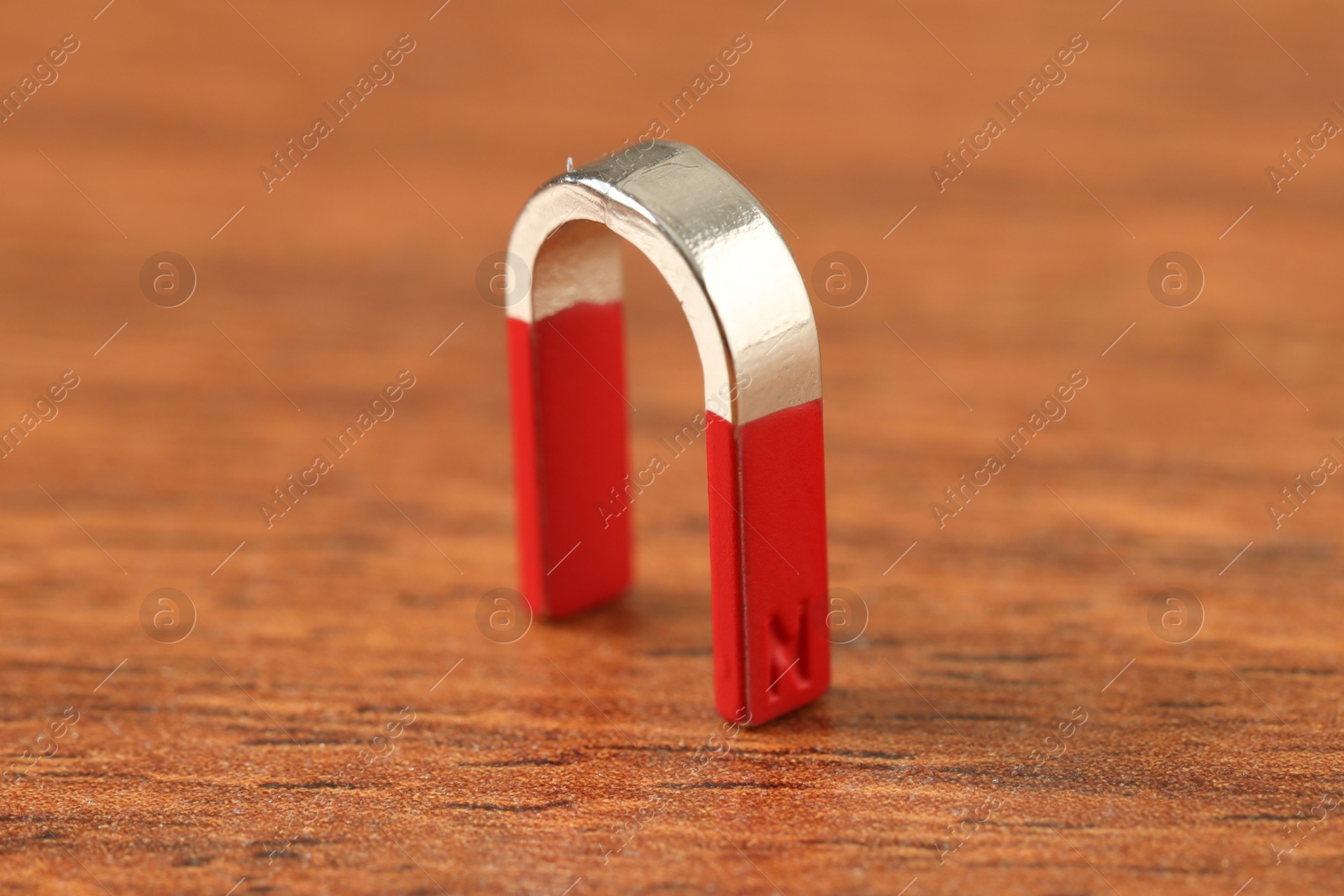 Photo of One horseshoe magnet on wooden table, closeup