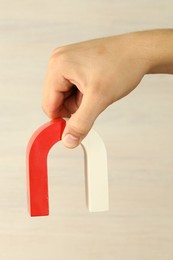 Photo of Man holding horseshoe magnet against light background, closeup