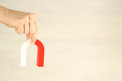 Photo of Man holding horseshoe magnet against light background, closeup. Space for text