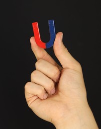 Photo of Man holding horseshoe magnet on dark background, closeup