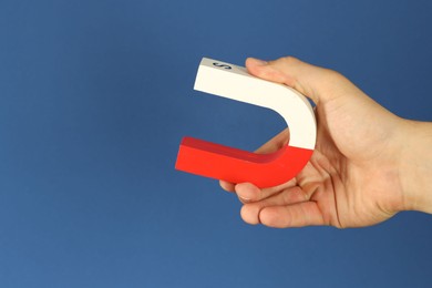 Photo of Man holding horseshoe magnet on blue background, closeup. Space for text