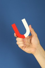 Photo of Man holding horseshoe magnet on blue background, closeup