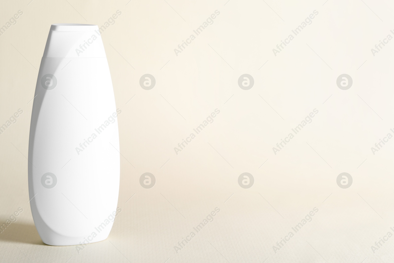 Photo of Shampoo in bottle on beige background, space for text