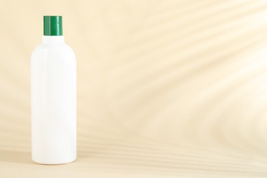 Photo of Shampoo in bottle on beige background, space for text