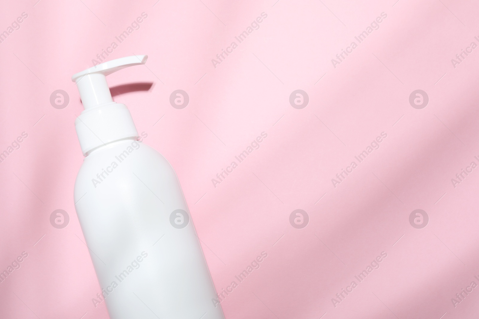 Photo of Shampoo in bottle on pink background, top view. Space for text