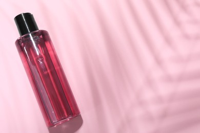 Photo of Shampoo in bottle on pink background, top view. Space for text