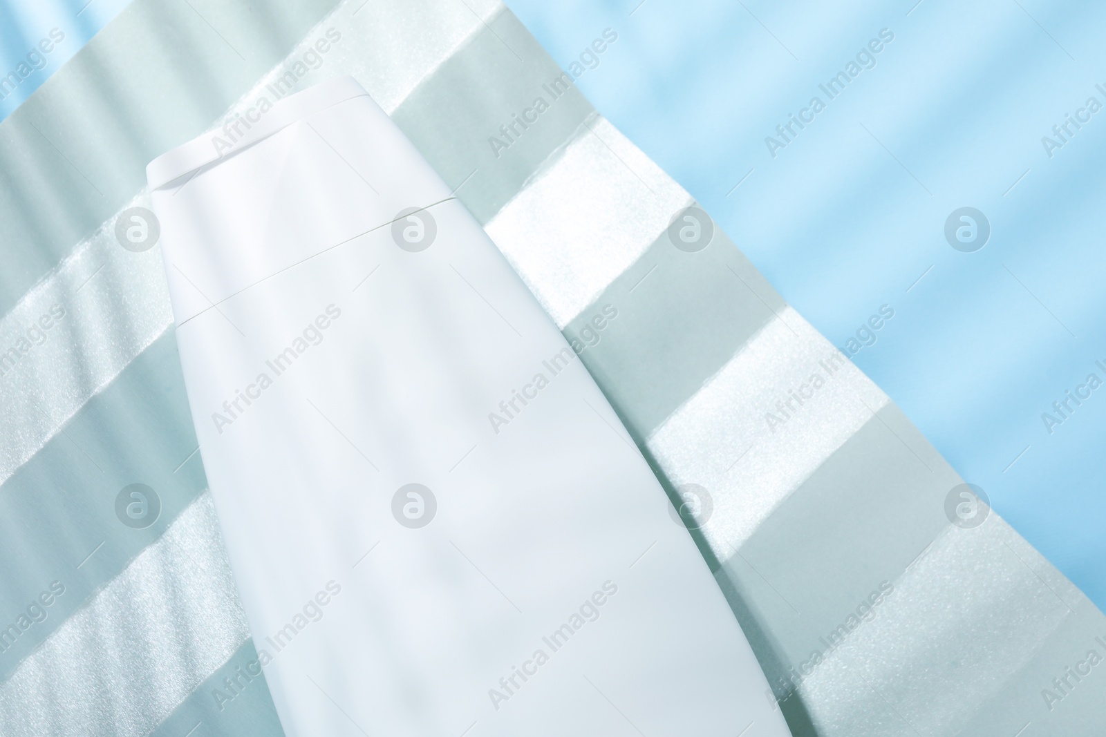 Photo of Shampoo in bottle on light blue background, top view