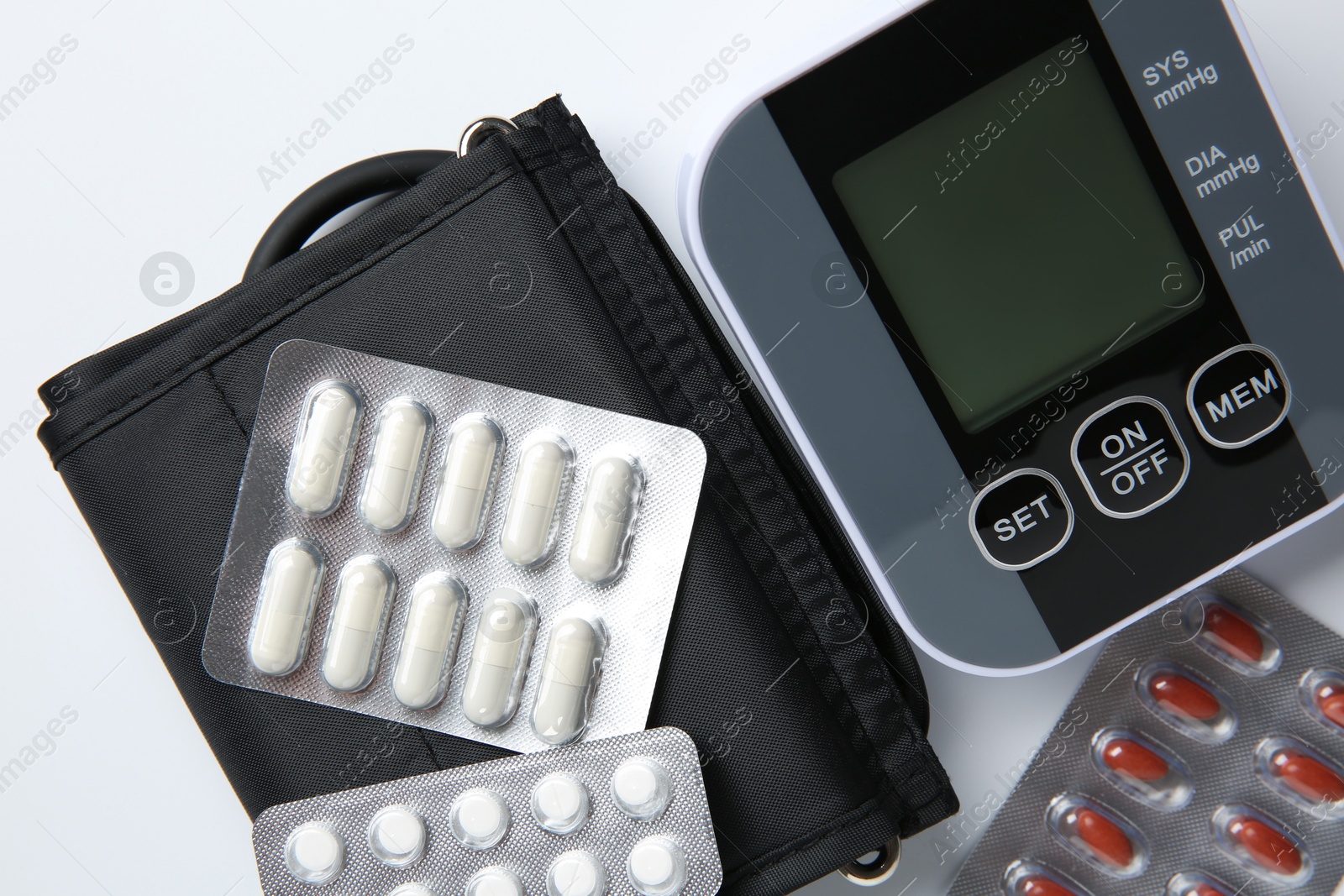 Photo of Blood pressure measuring device and pills on white background, top view