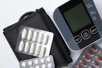 Photo of Blood pressure measuring device and pills on white background, top view