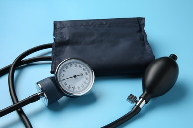 Photo of Blood pressure measuring device on light blue background, closeup