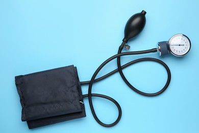 Photo of Blood pressure measuring device on light blue background, top view