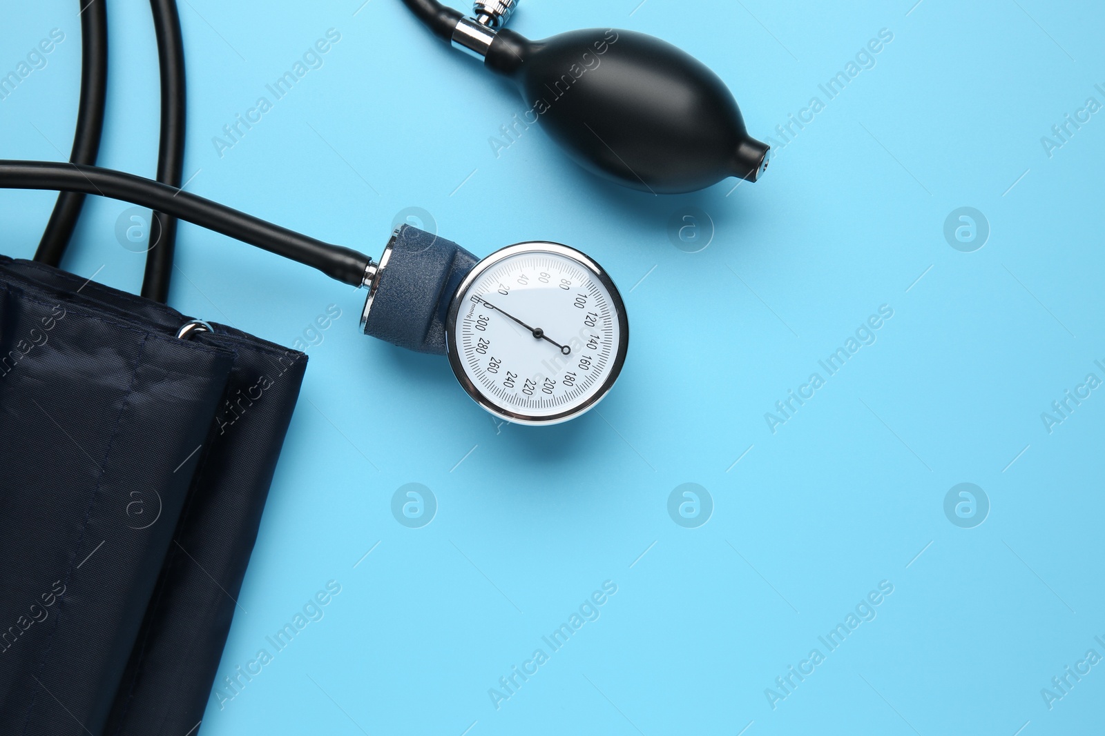 Photo of Blood pressure measuring device on light blue background, top view. Space for text