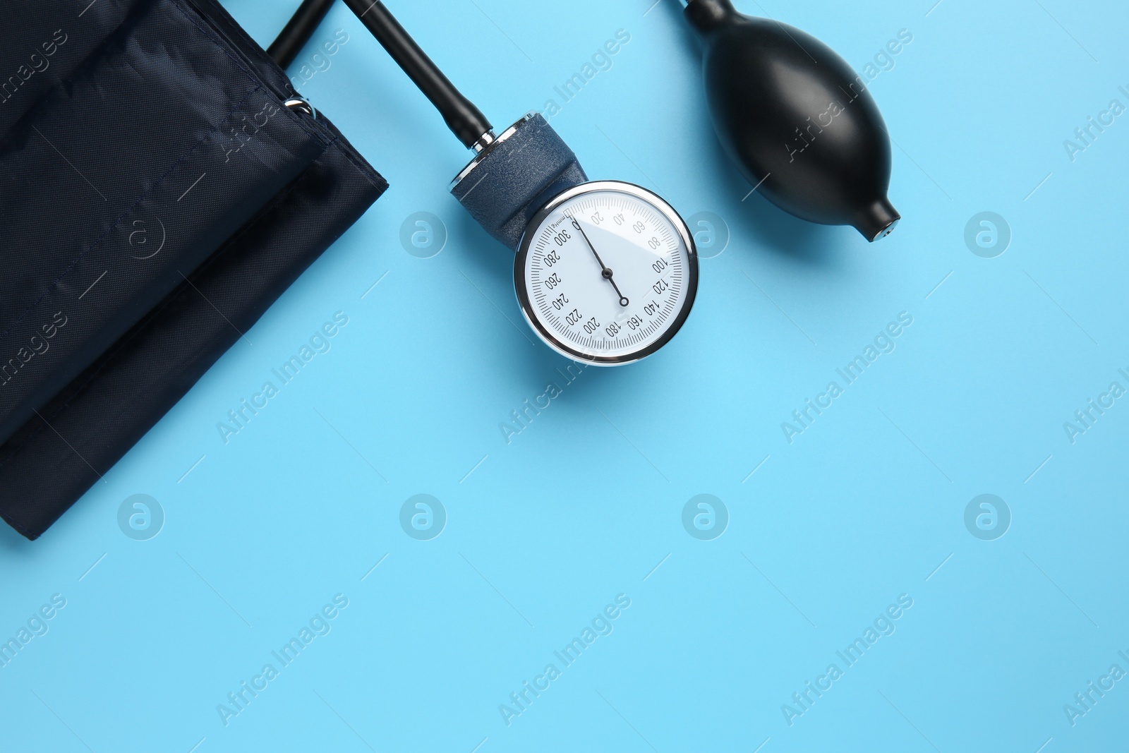 Photo of Blood pressure measuring device on light blue background, top view. Space for text