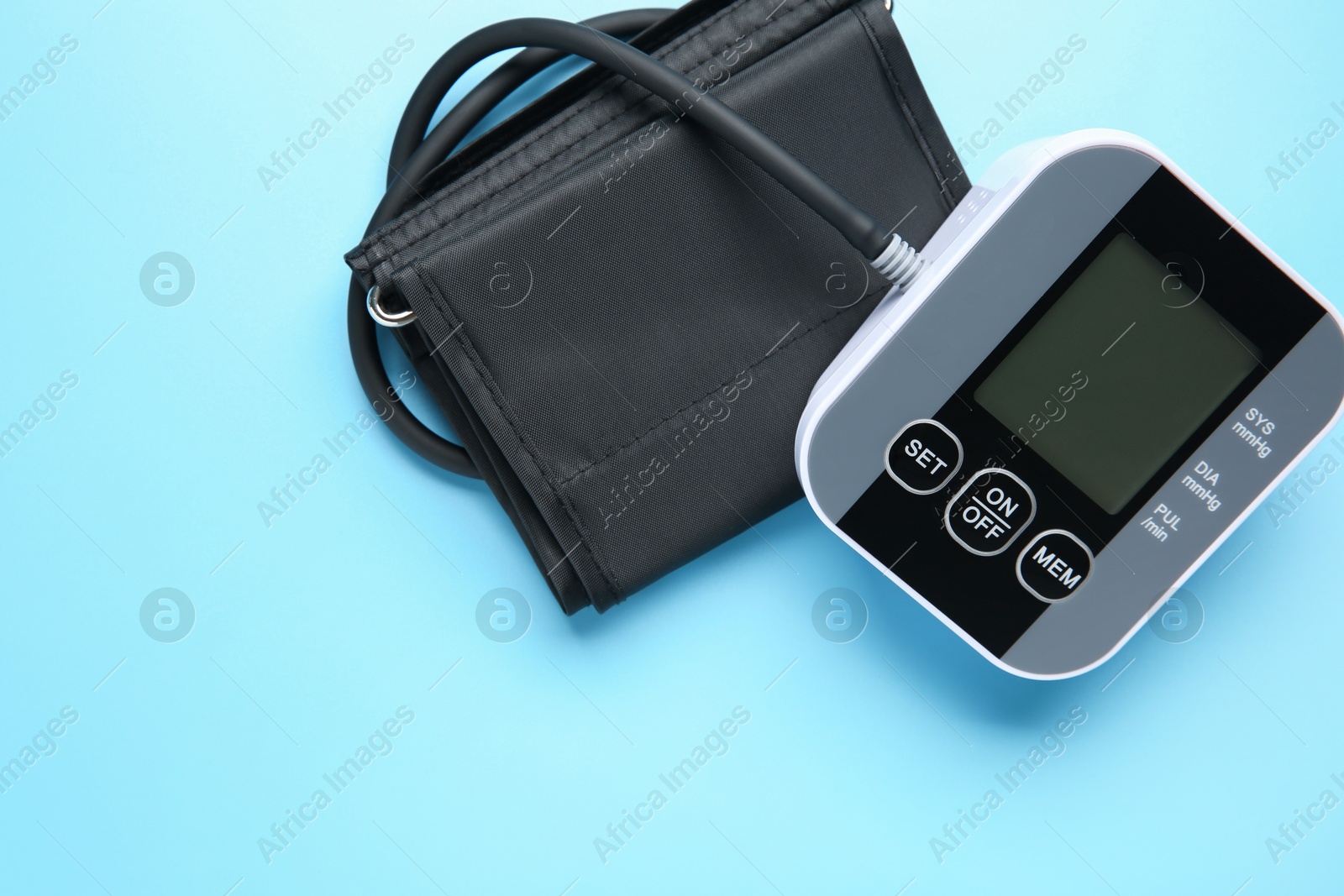 Photo of Blood pressure measuring device on light blue background, top view