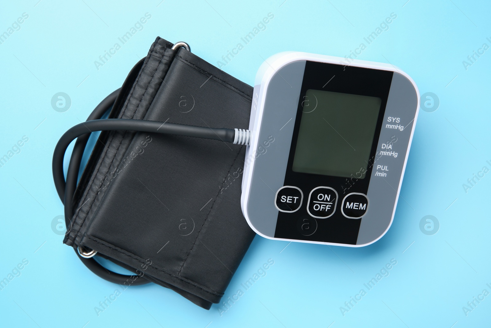 Photo of Blood pressure measuring device on light blue background, top view